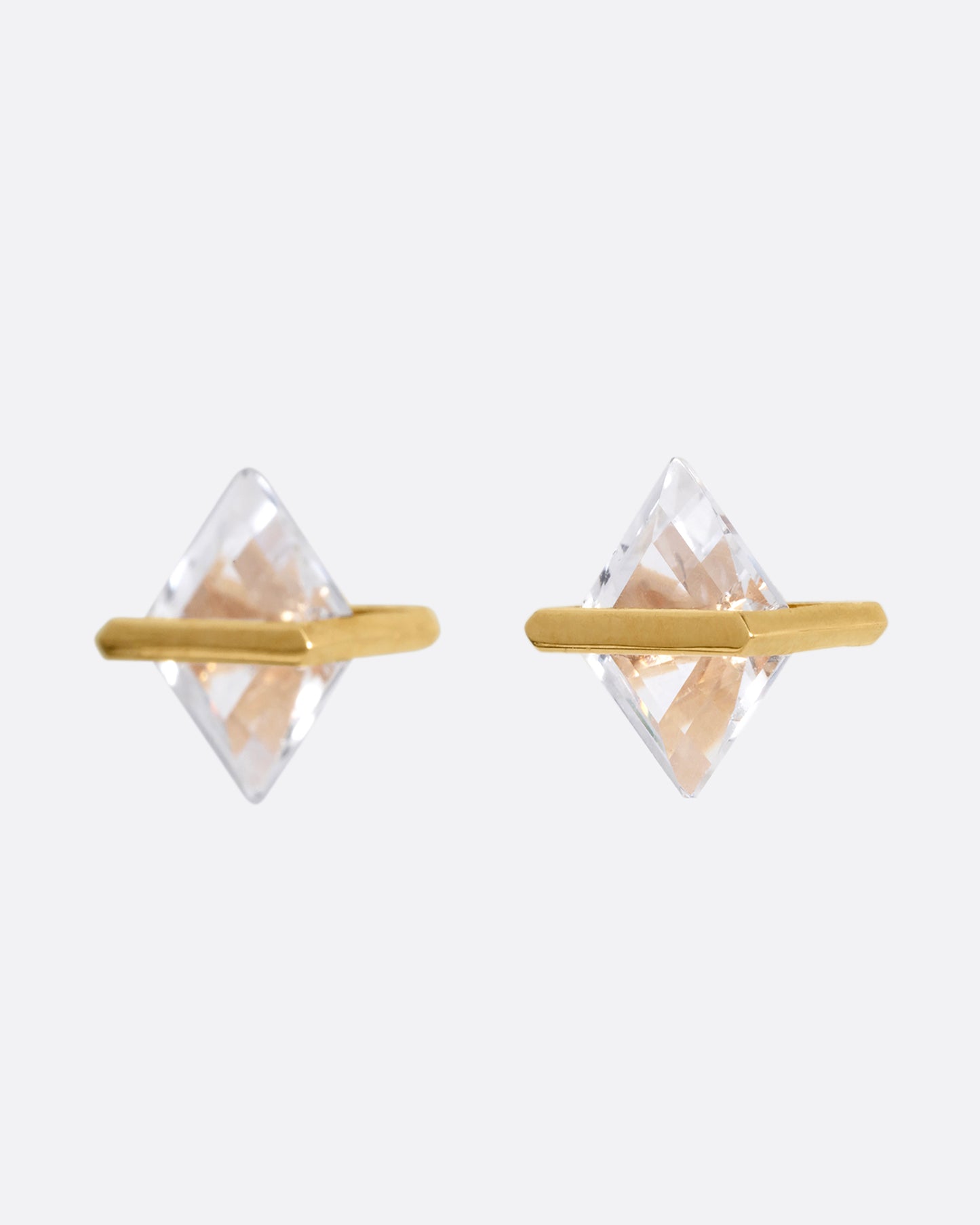 A pair of rhombus shaped quartzes, each in an open yellow gold bar stud earring setting. Shown from the side.