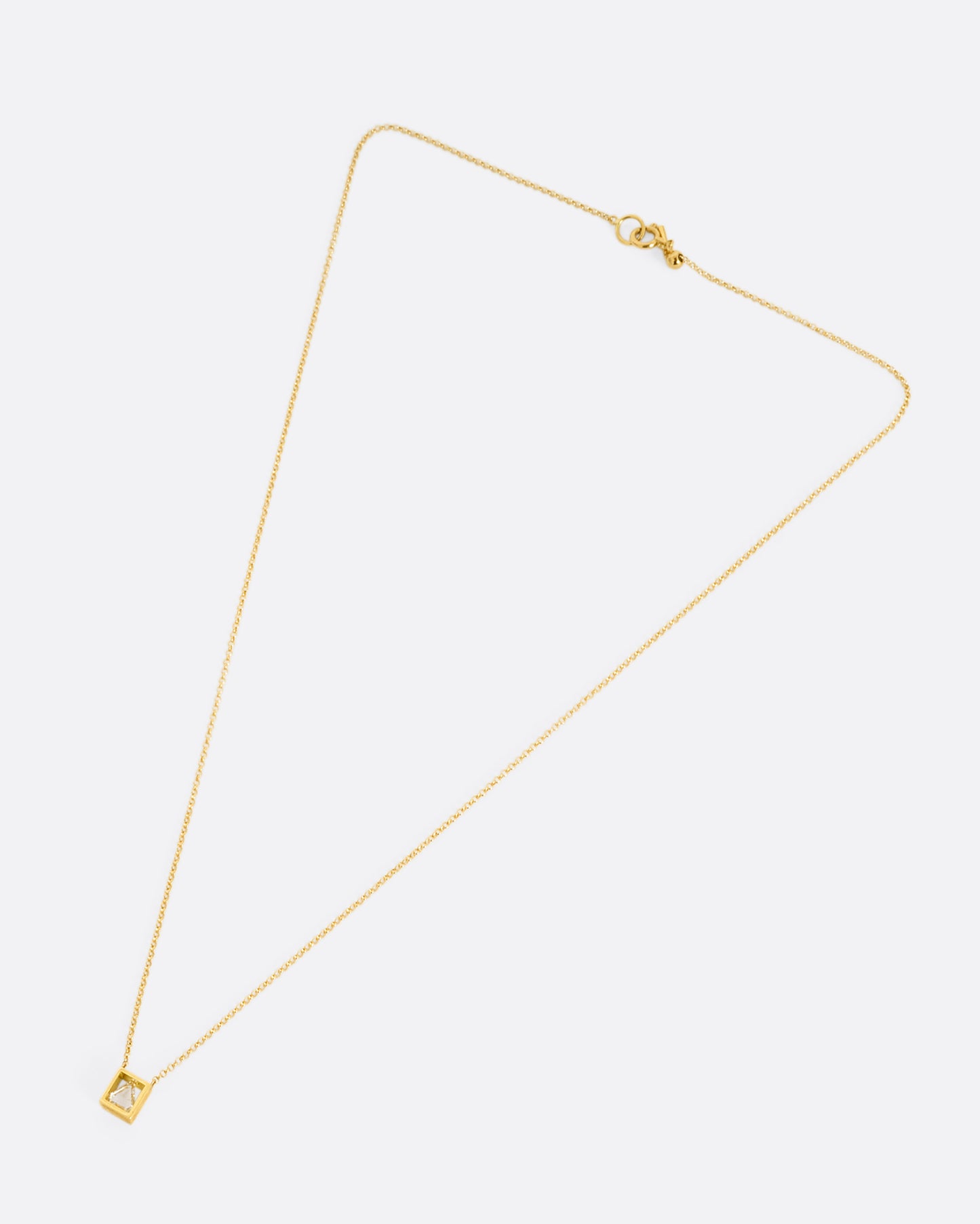 A yellow gold cable chain necklace with a triangular diamond in an open setting, shown from the front.