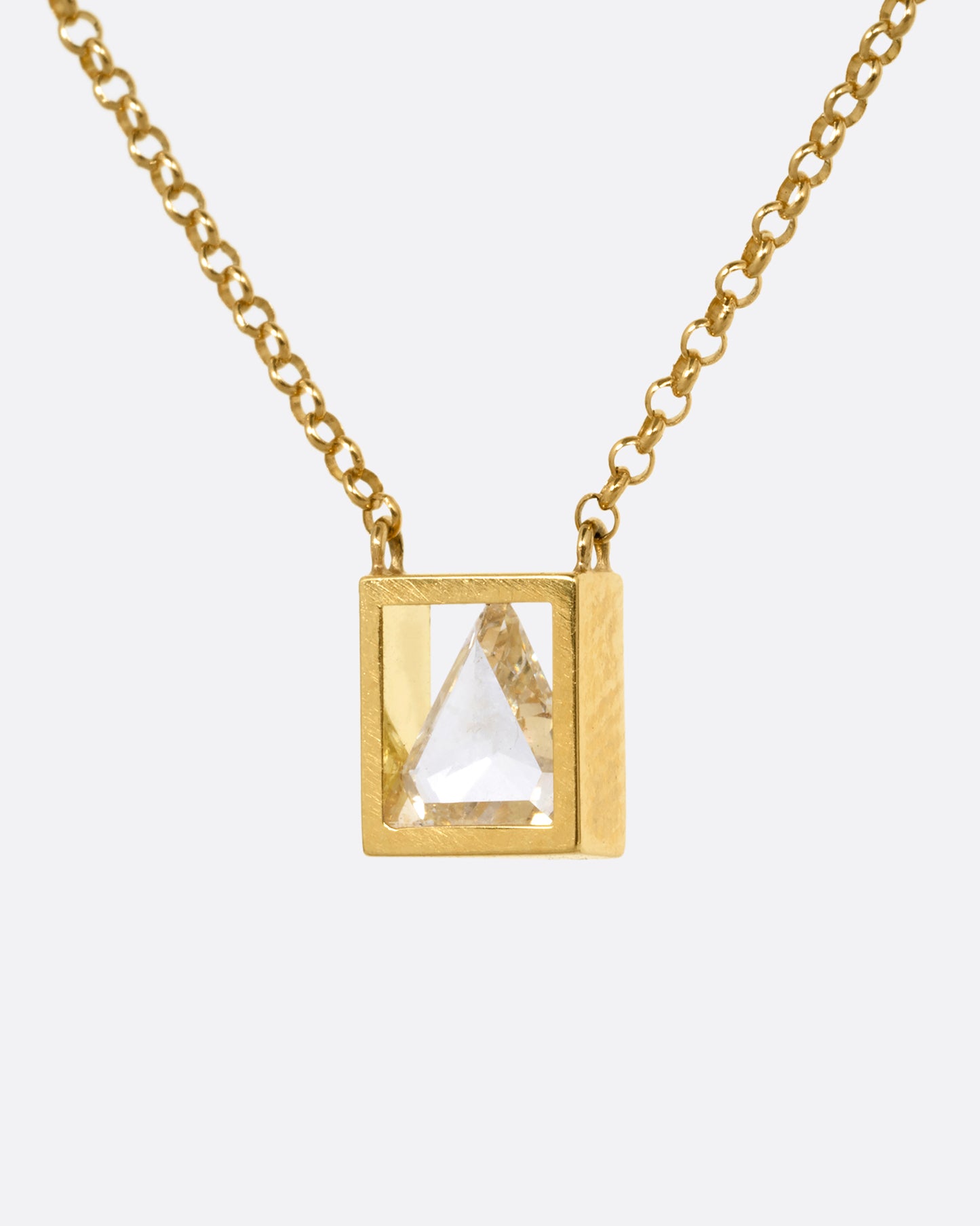 A yellow gold cable chain necklace with a triangular diamond in an open setting, shown from the side.