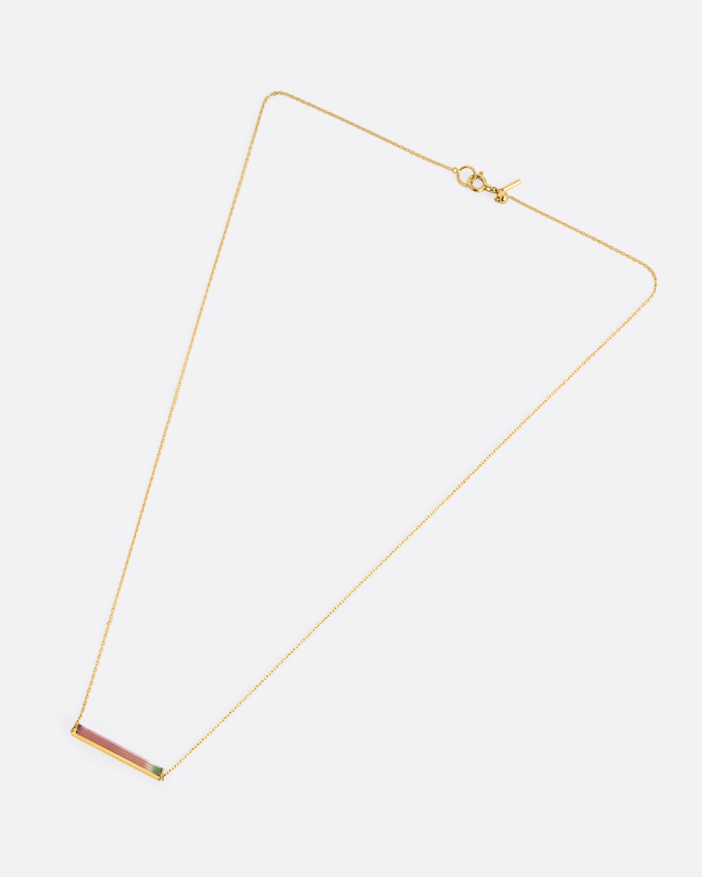 A yellow gold cable chain necklace with a watermelon tourmaline and gold bar, shown from the front.