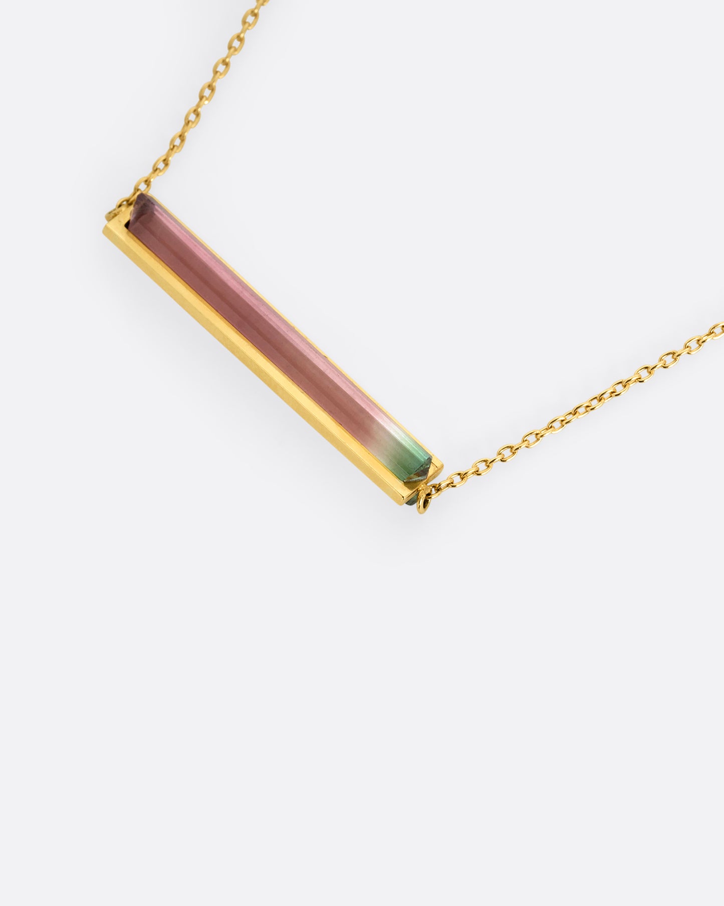 A yellow gold cable chain necklace with a watermelon tourmaline and gold bar, shown from the front at an angle.