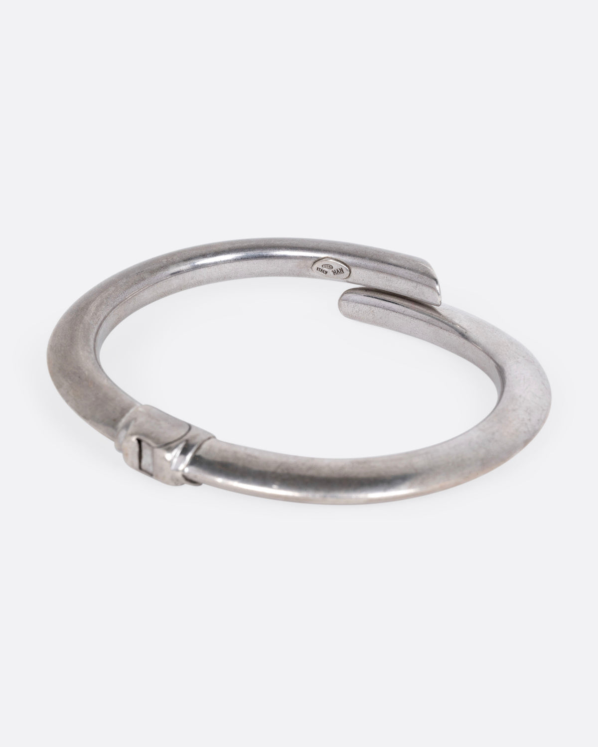 A silver wrap bracelet with hinged back, shown from the side.