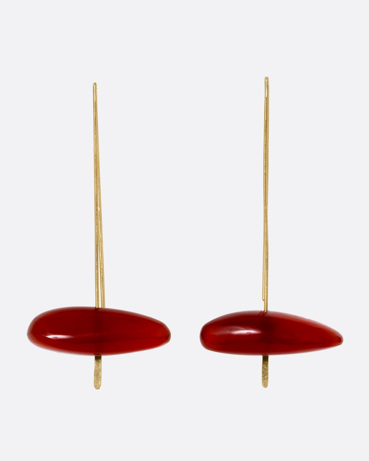 A pair of long yellow gold earrings with freeform carnelians at each base, shown from the front.
