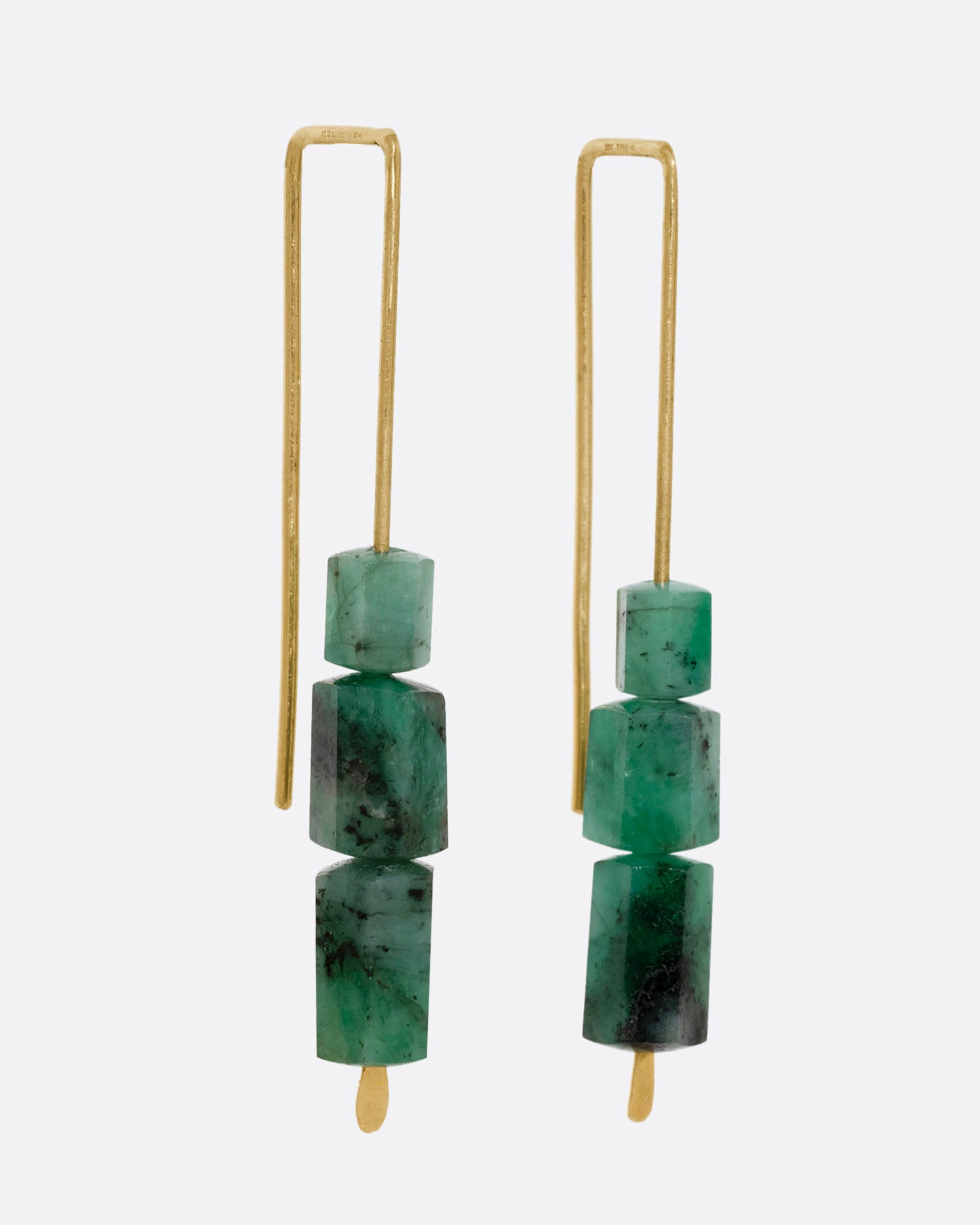 A pair of yellow gold hook earrings with three stacked freeform emeralds. Shown from the side.