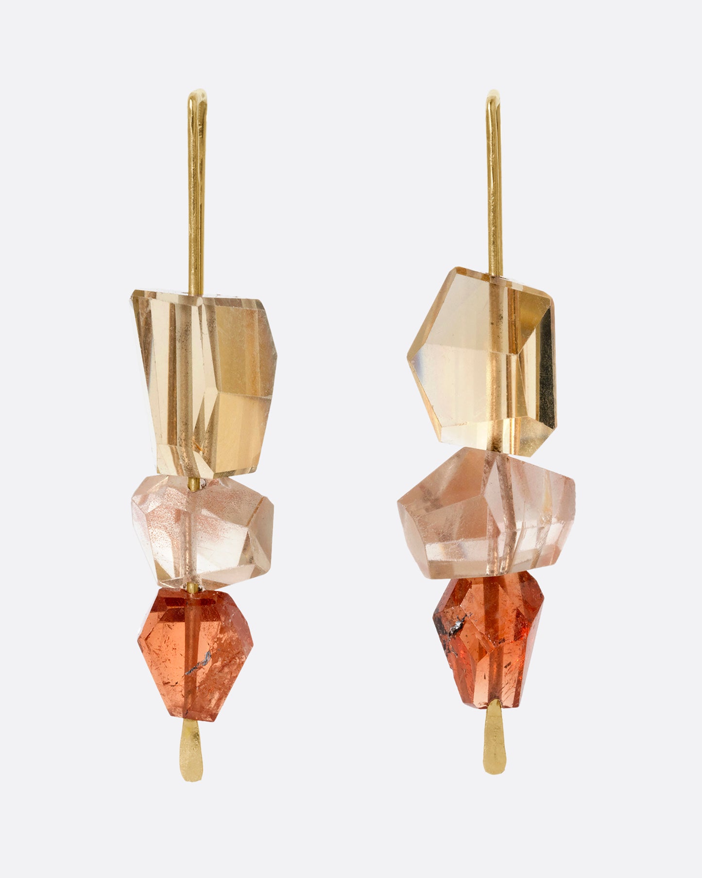A pair of yellow gold hook earrings with a stack of three sunstones and hessonite garnets. Shown from the front.