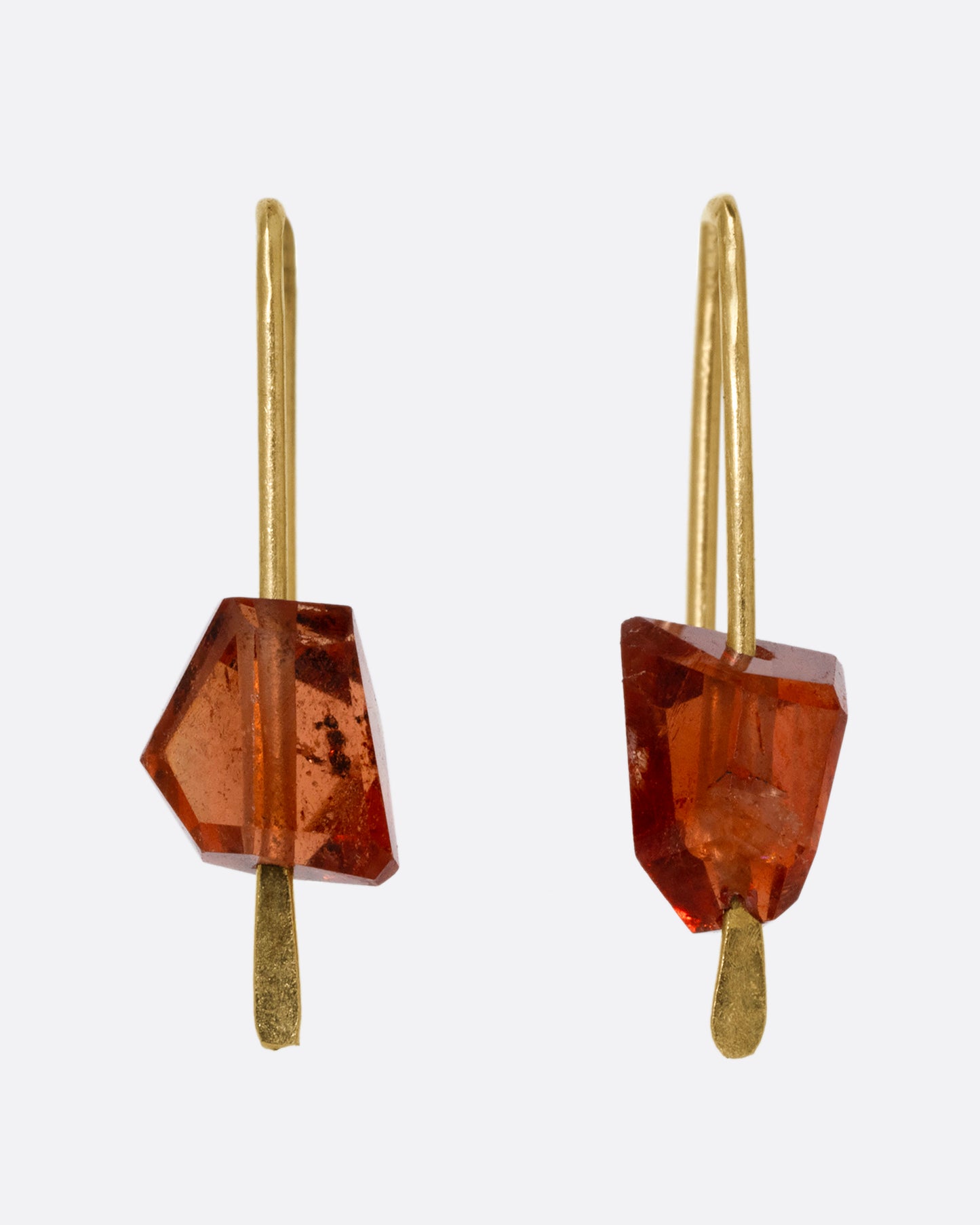 A pair of yellow gold hook earrings with angular hessonite garnets, shown from the front.