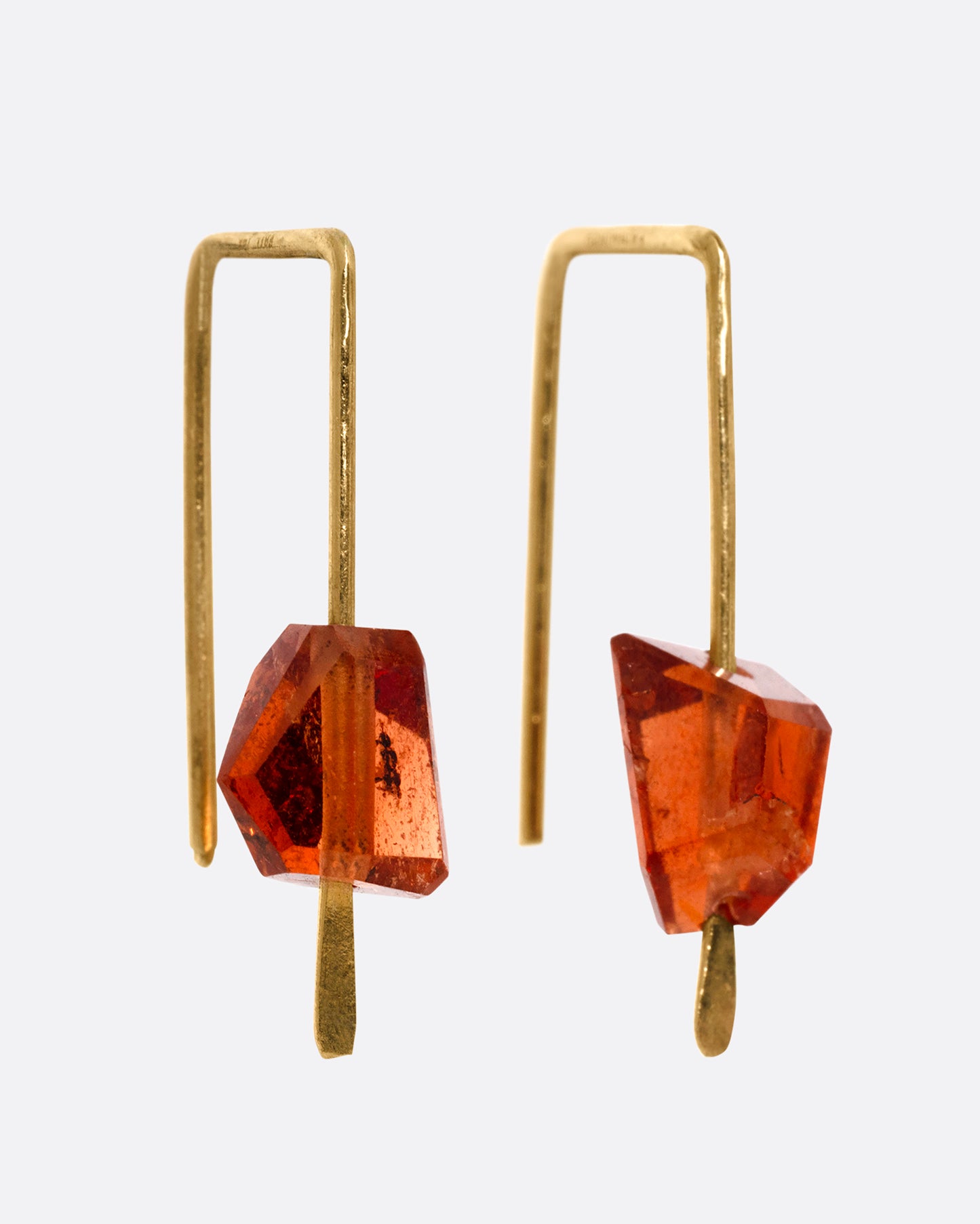 A pair of yellow gold hook earrings with angular hessonite garnets, shown from the side.