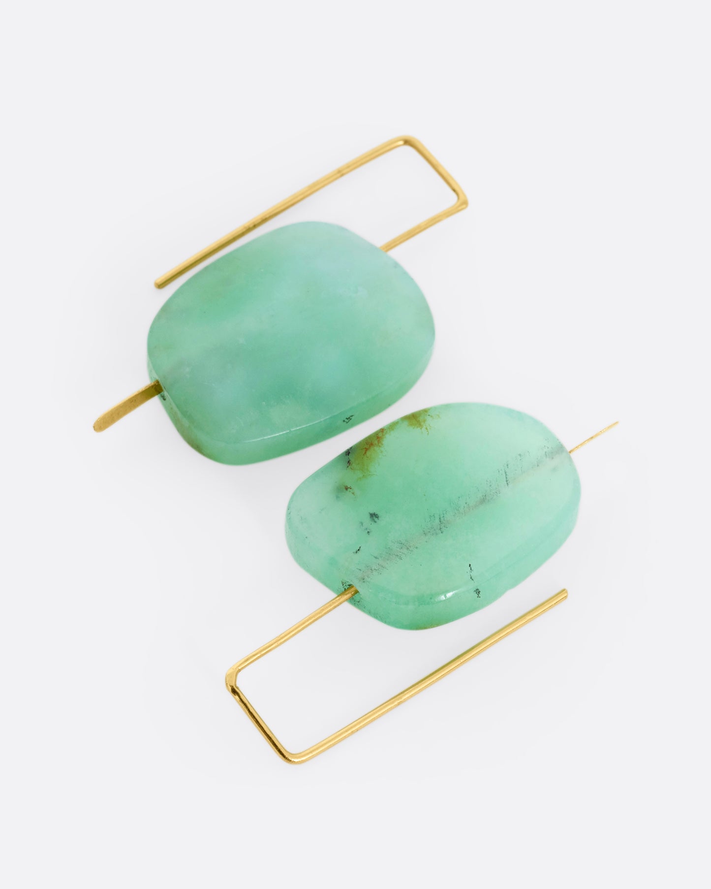 A pair of yellow gold hook earrings with a single freeform chrysoprase on each.
Shown lying flat.