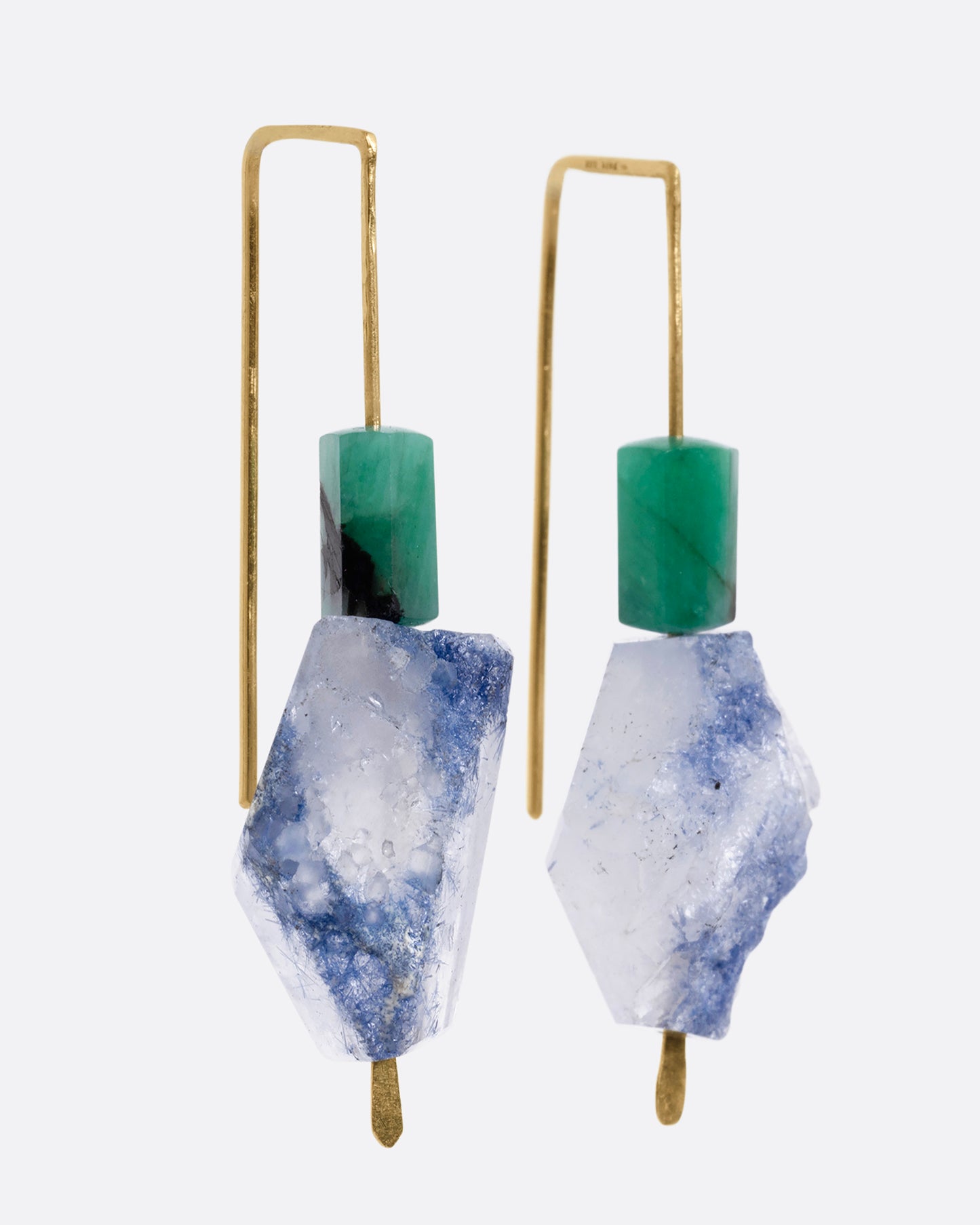A pair of yellow gold hook earrings with a freeform dumortierite and emerald on each. Shown from the side.
