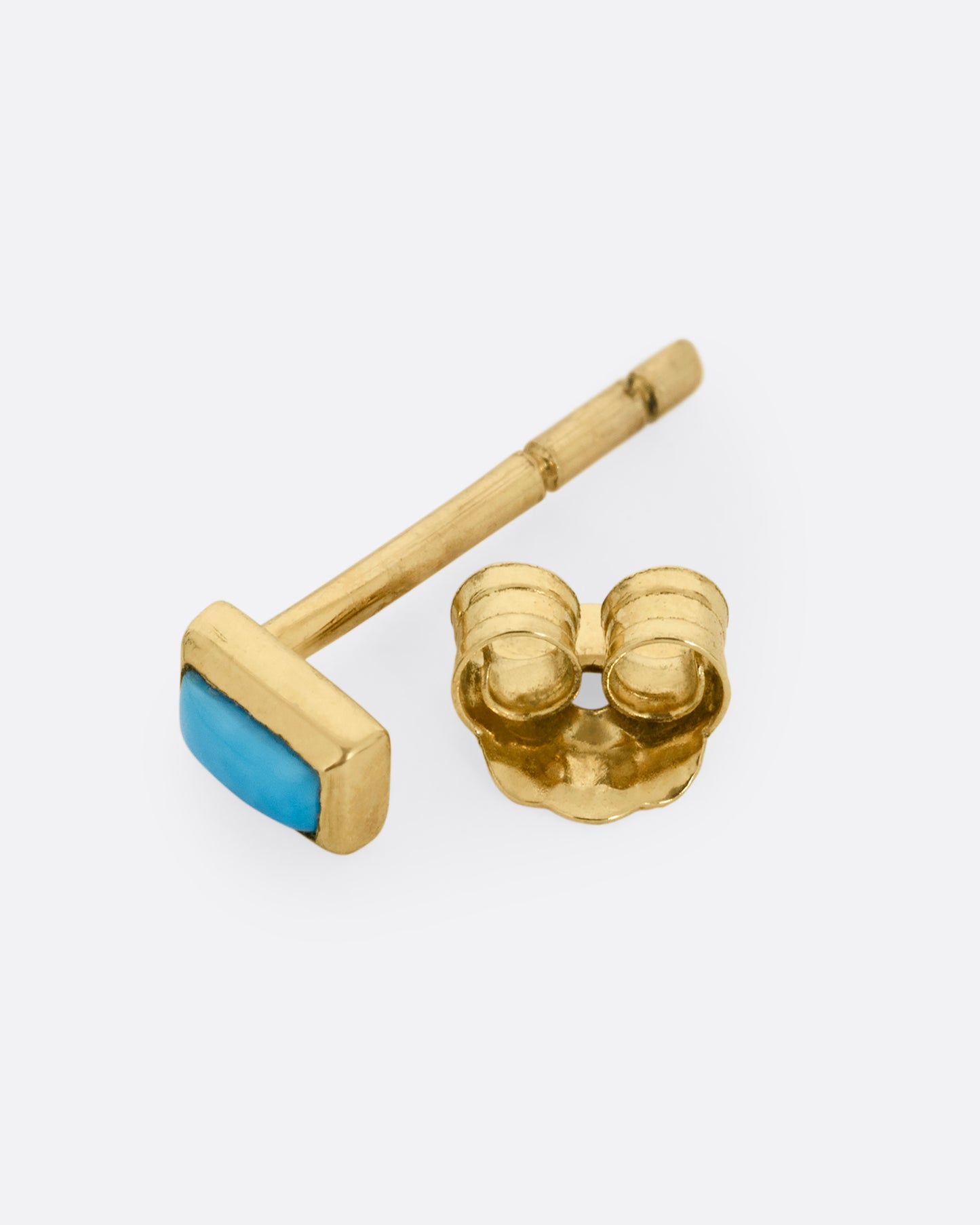 A yellow gold stud earring with a baguette cut turquoise, shown open on its side.