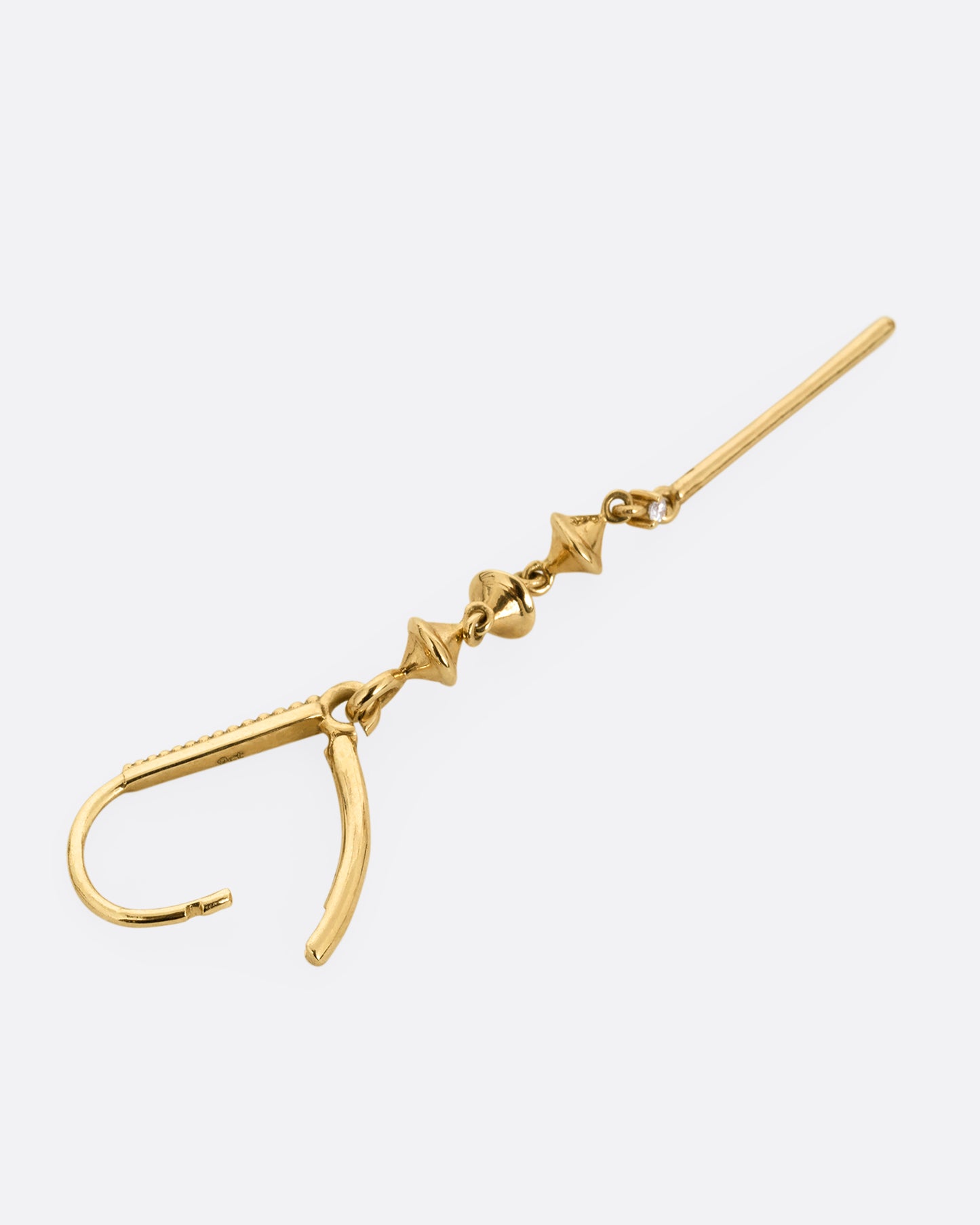 A yellow gold hook earring with three gold charms, a diamond, and long yellow gold bar, shown open lying on its side.