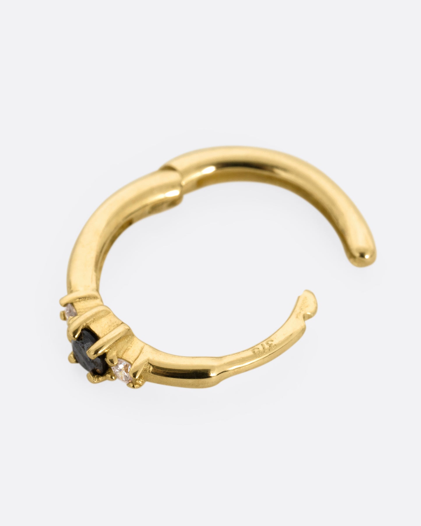 A yellow gold huggie hoop with two white diamonds and a black diamond, shown from the side open.