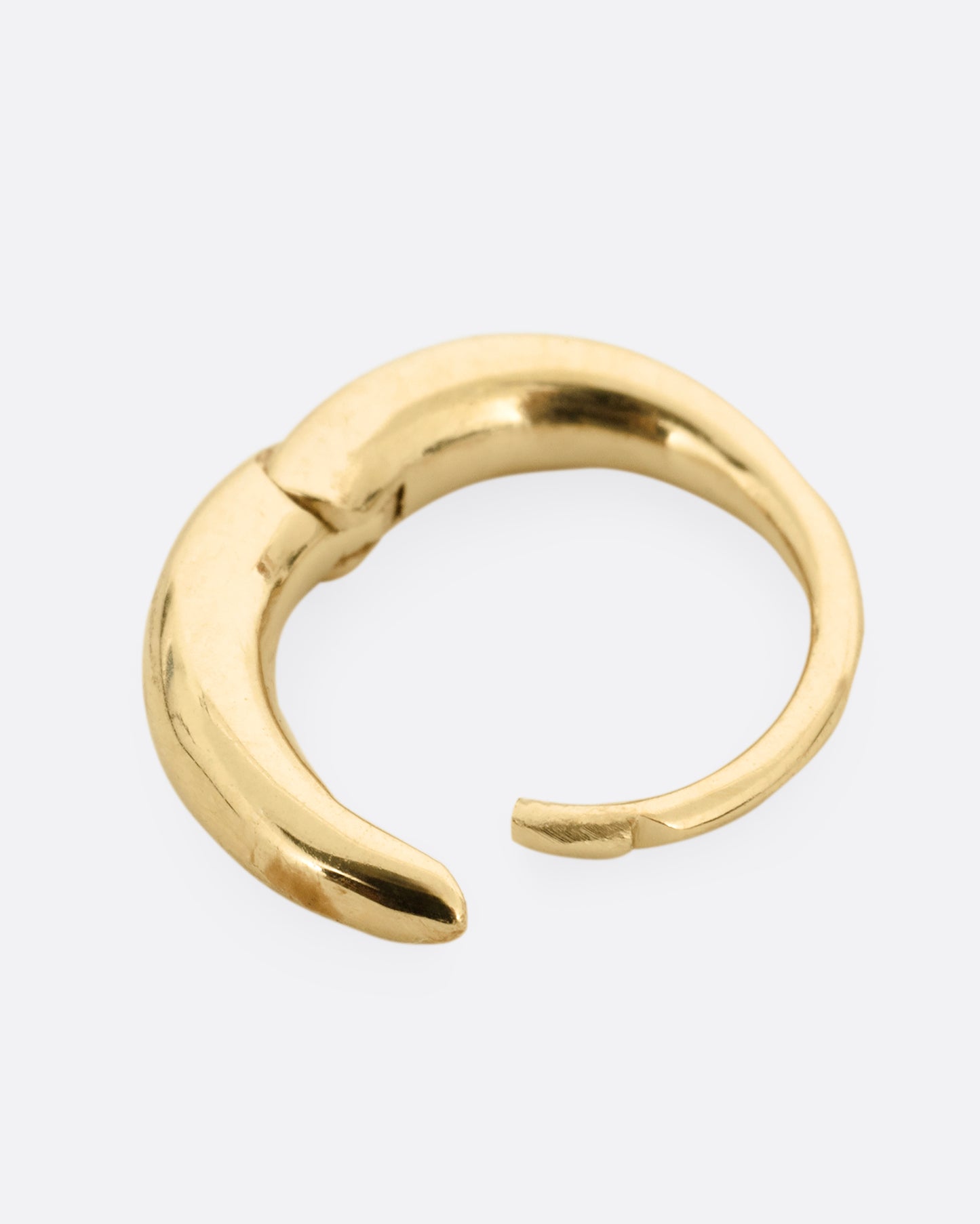 A yellow gold tapered hoop earring with a queue of graduated diamonds, shown from the side open.