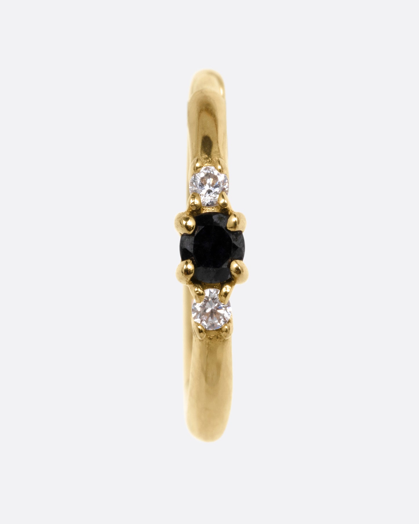 A yellow gold huggie hoop with two white diamonds and a black diamond, shown from the front.
