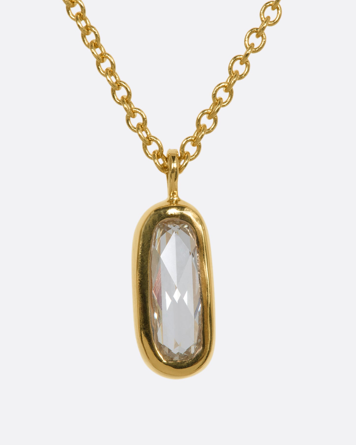 A yellow gold necklace with a rose cut solitaire diamond pendant and a cluster of diamonds on the chain. View close up of the front.
