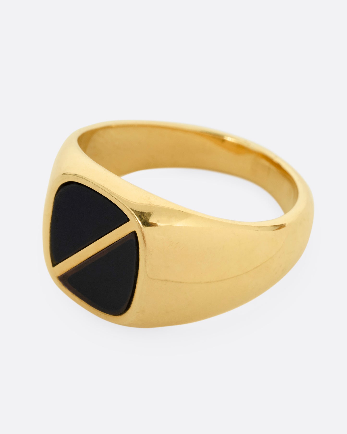 A yellow gold signet ring with a square onyx inlaid face and a diagonal split through its center. Shown from the side.