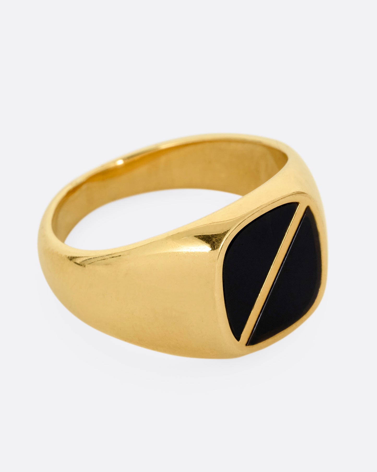 A yellow gold signet ring with a square onyx inlaid face and a diagonal split through its center. Shown from the side.