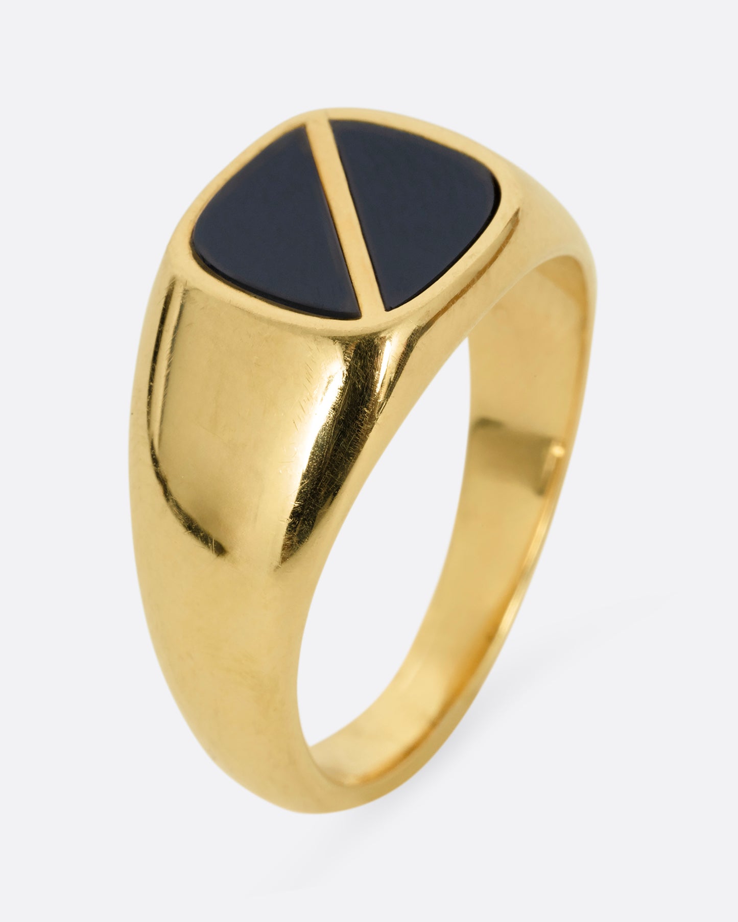 A yellow gold signet ring with a square onyx inlaid face and a diagonal split through its center. Shown standing up from the side.