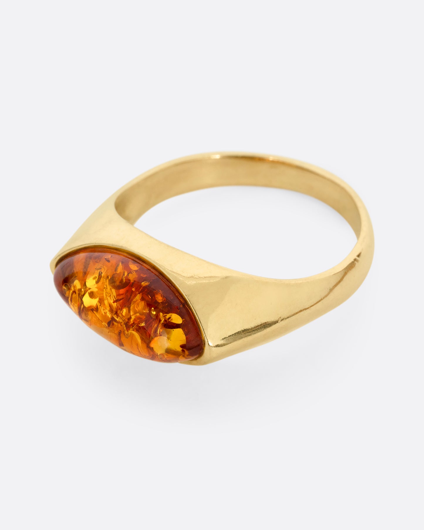 A yellow gold ring with an oval amber, shown from the side.