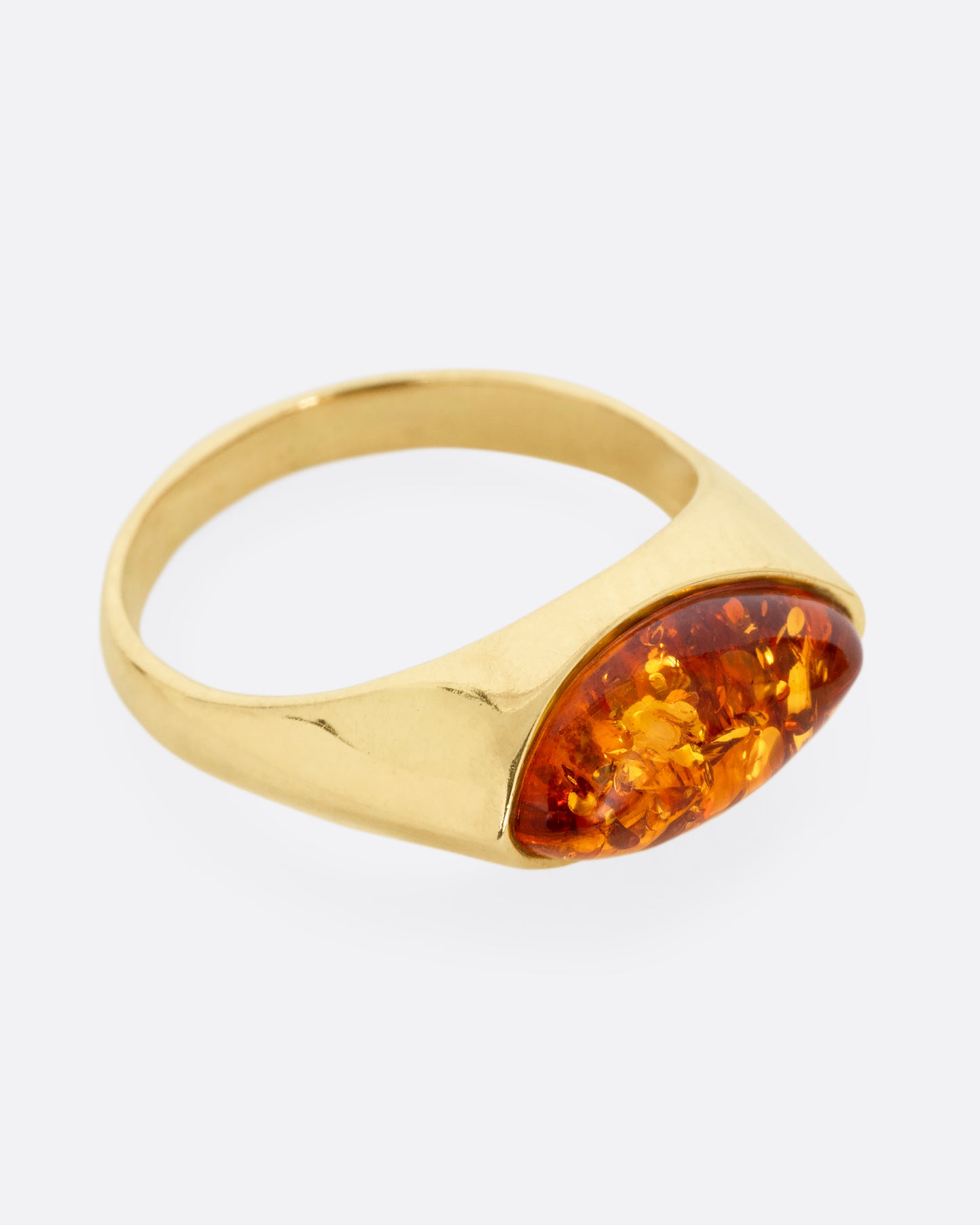 A yellow gold ring with an oval amber, shown from the side.