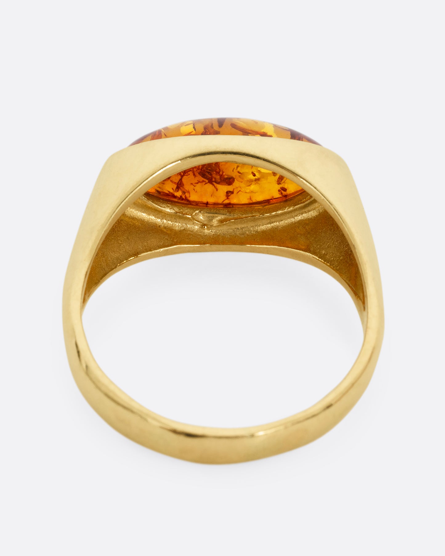 A yellow gold ring with an oval amber, shown from the back.