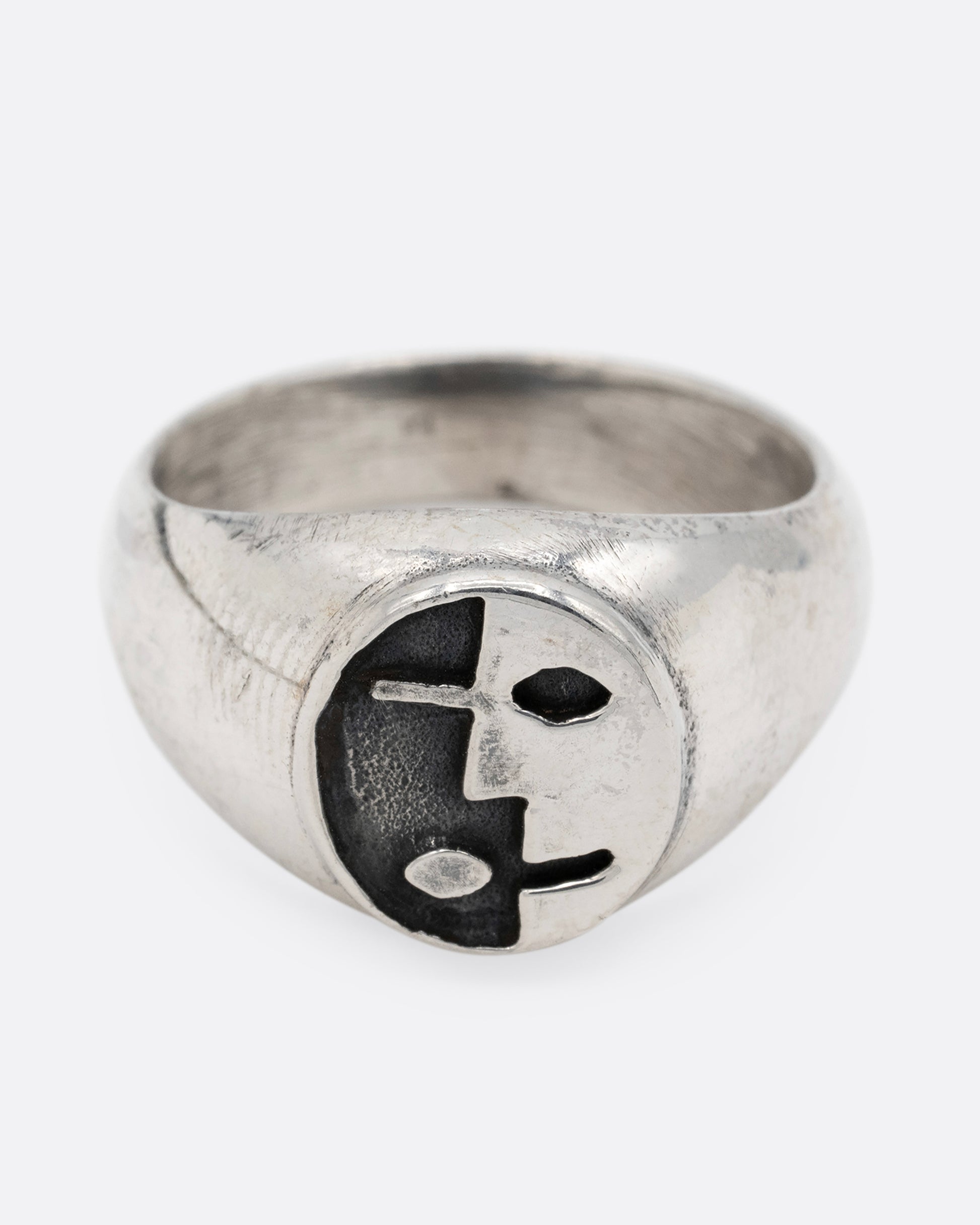 A silver signet ring with yin yang faces, shown from the front.