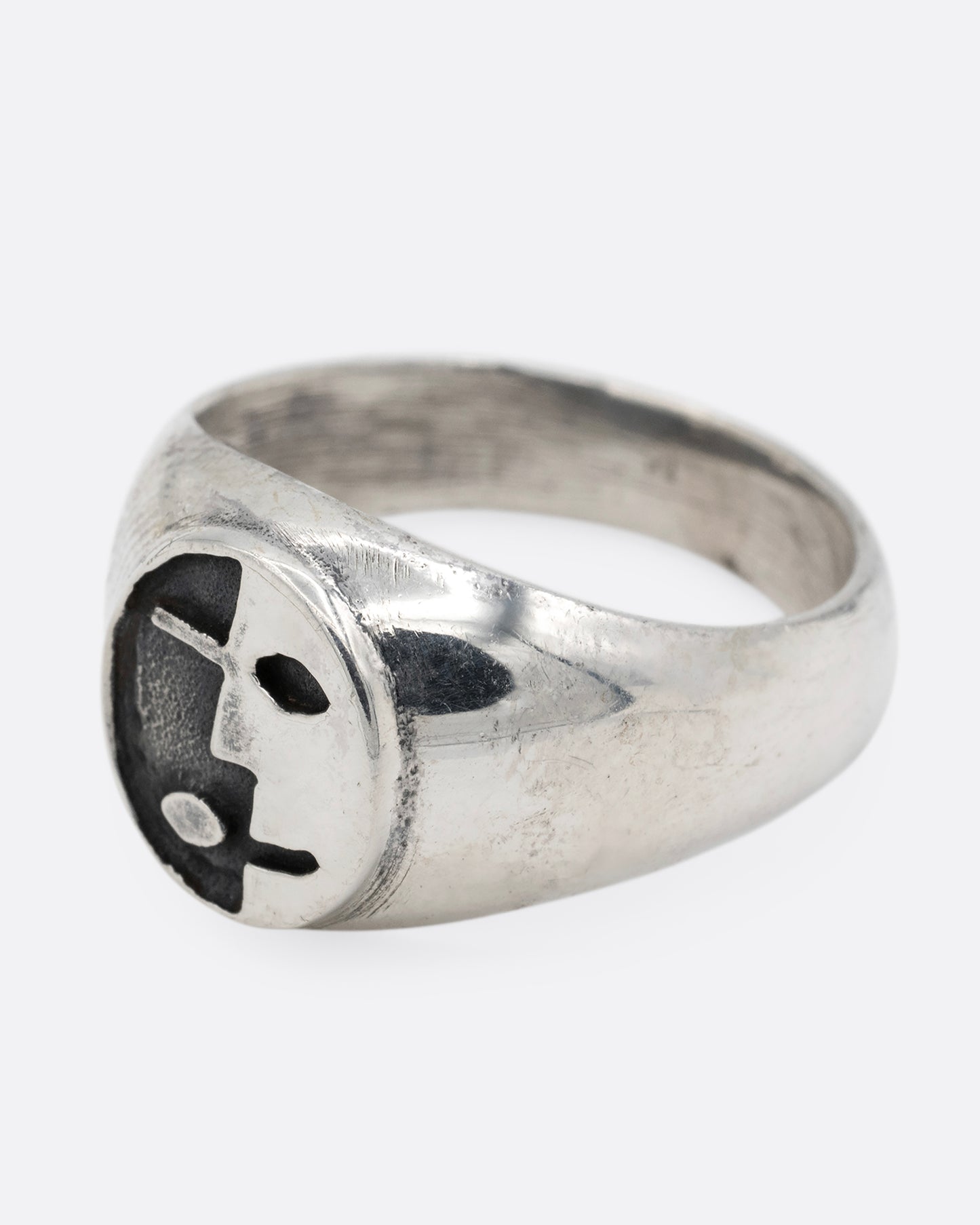 A silver signet ring with yin yang faces, shown from the side.