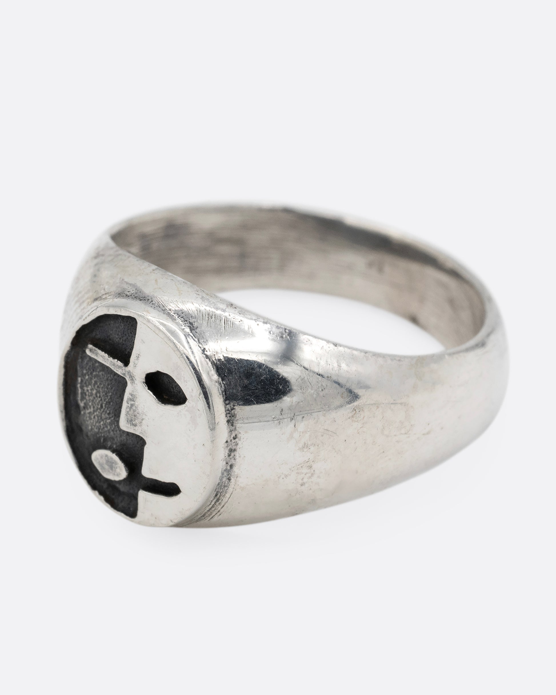A silver signet ring with yin yang faces, shown from the side.
