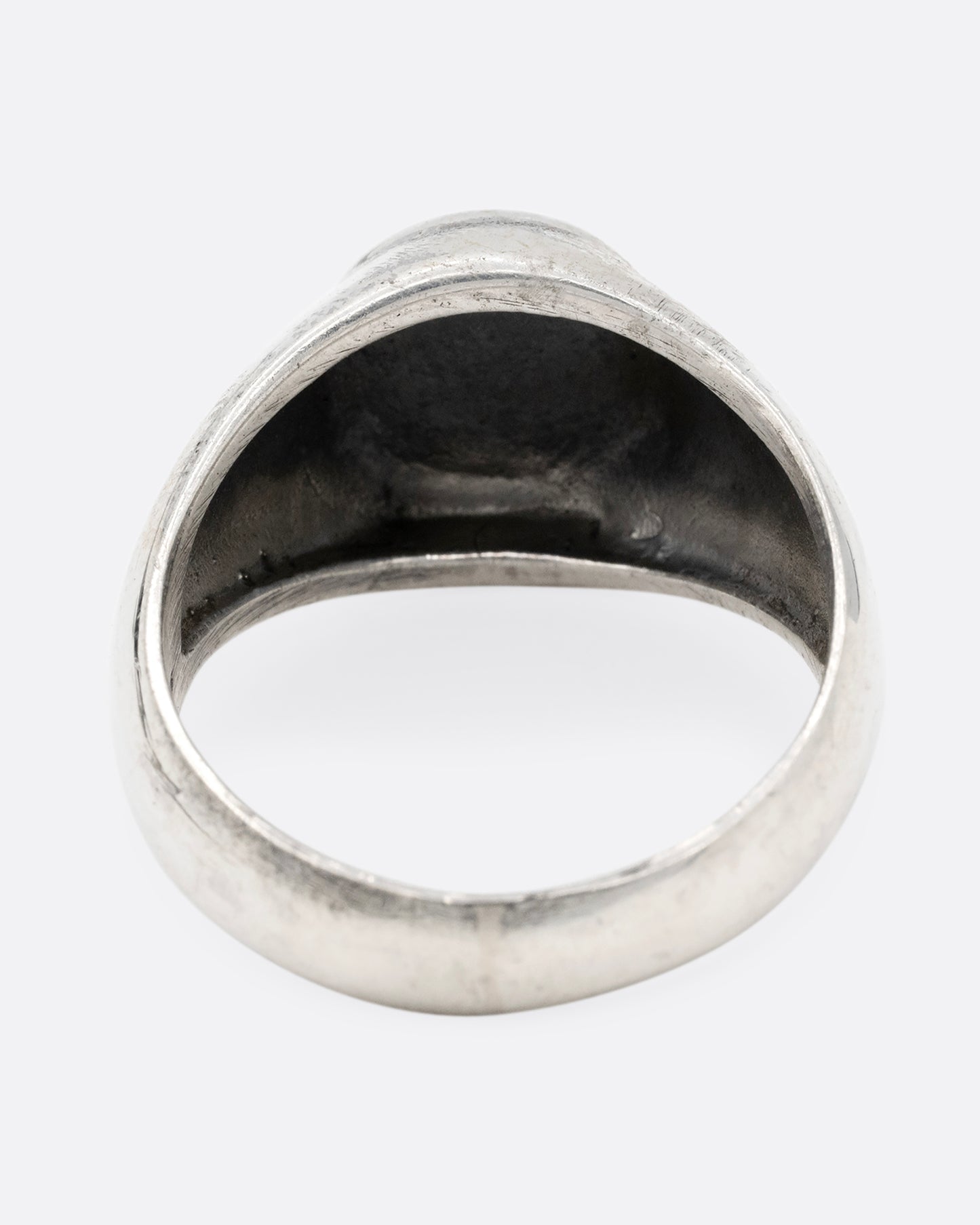 A silver signet ring with yin yang faces, shown from the back.