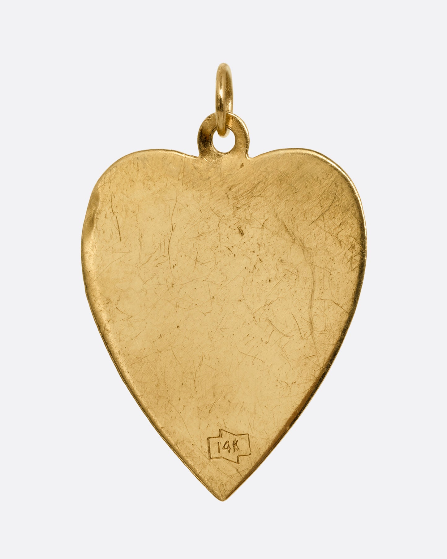 A yellow gold heart shaped pendant with a ruby and small arrow- stricken heart at the center. Shown from the back.