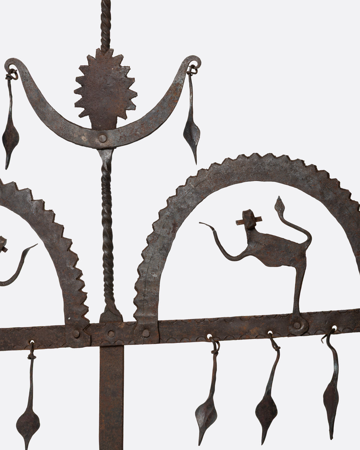 A close up of a cast iron hanging candle holder with small figures and fringe at its base and three spots for tea lights.