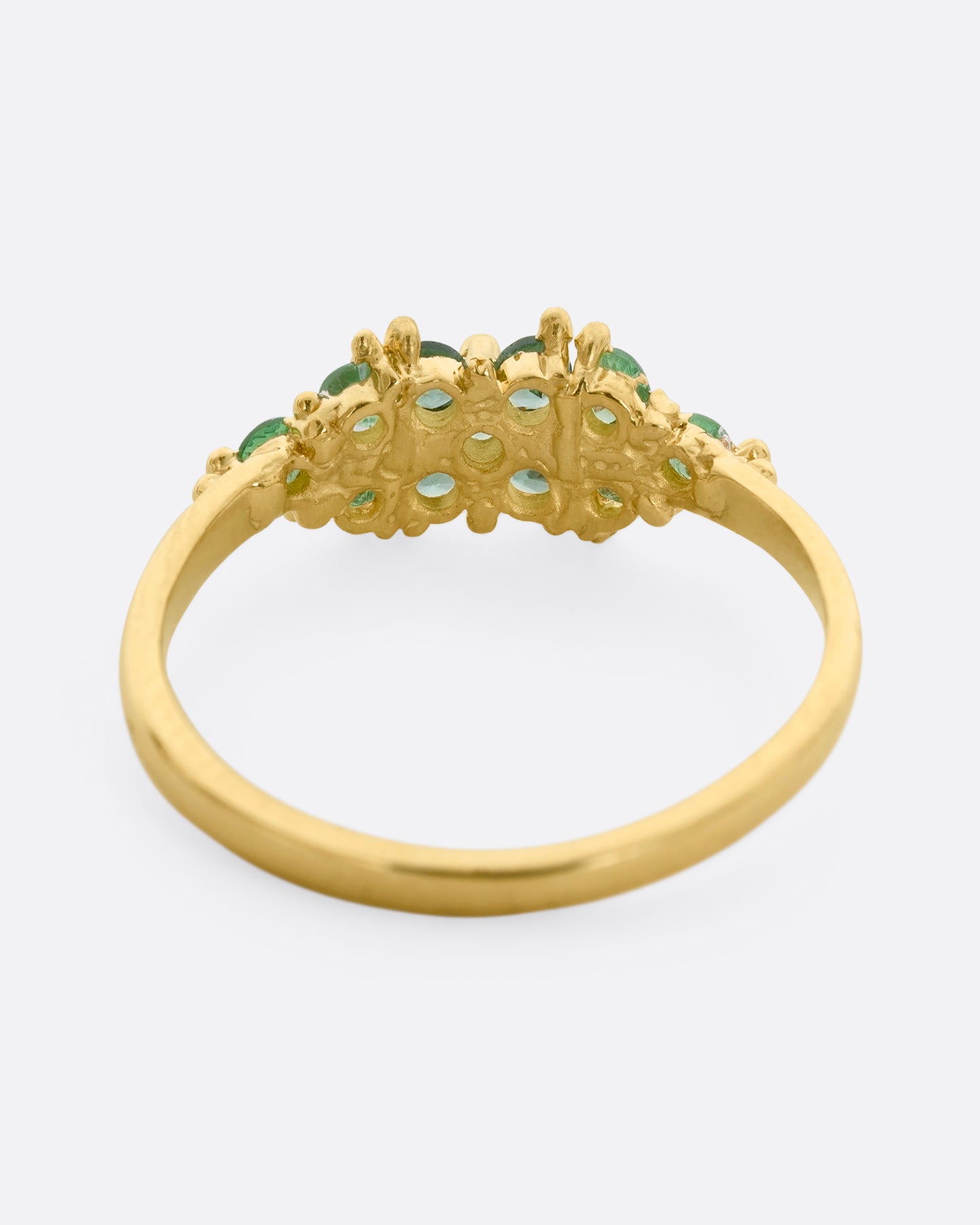 A yellow gold ring with a cluster of eleven green sapphires and tsavorite. Shown from the back.