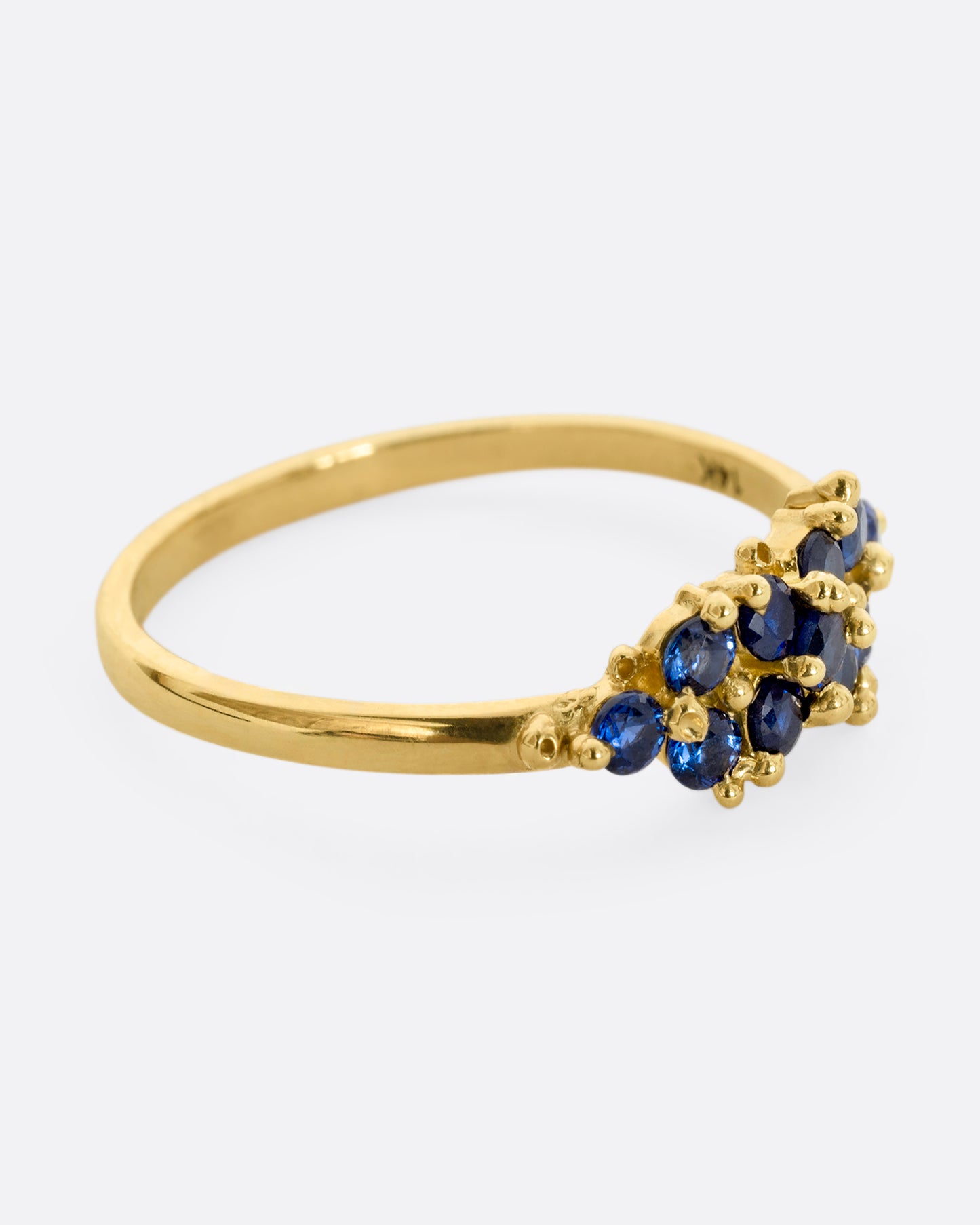 A yellow gold ring with a cluster of eleven blue sapphires. Shown from the side.