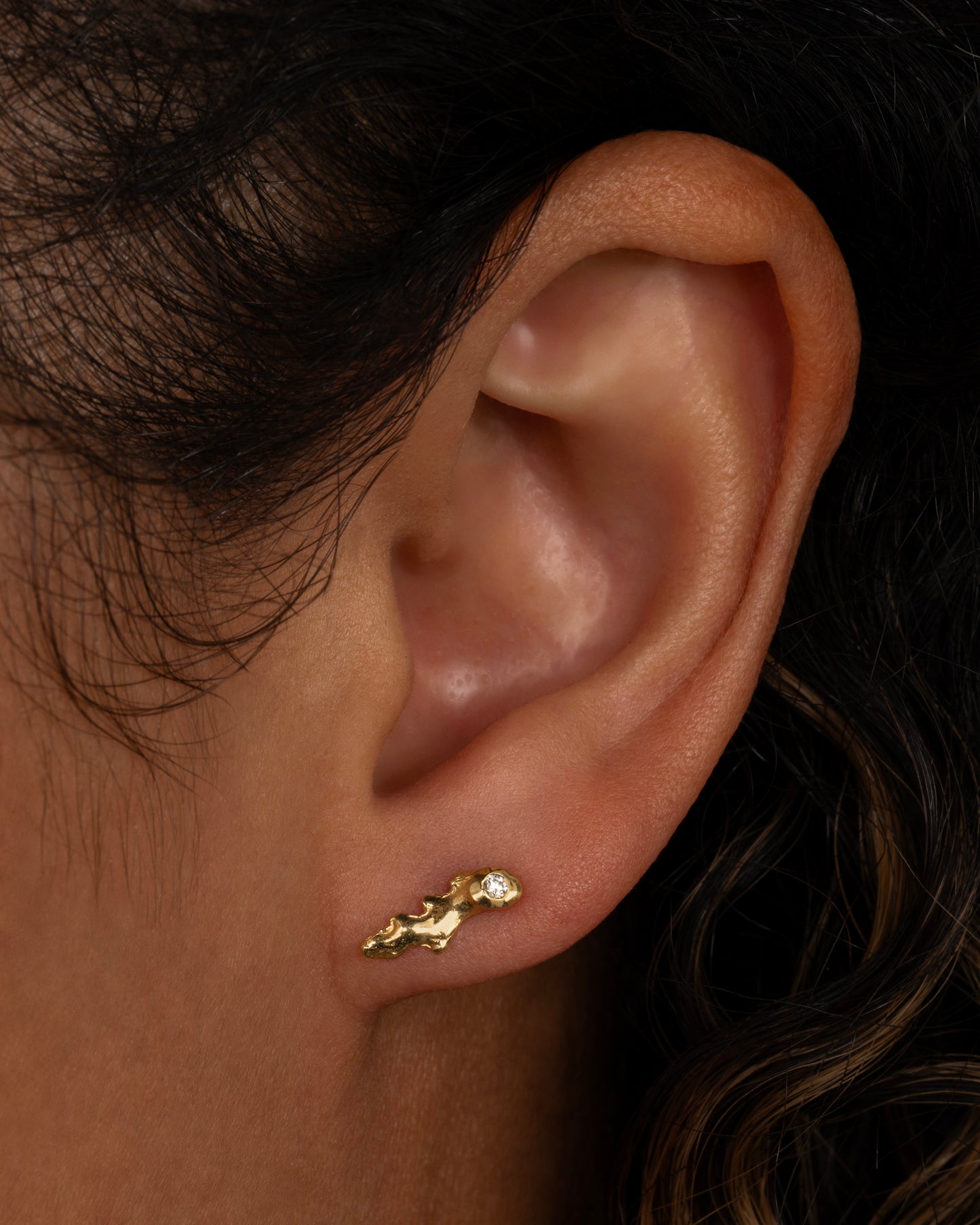 This pair of 18k gold studs dotted with round diamonds looks like tiny pieces of coral adorning your ear. Shown on an ear.