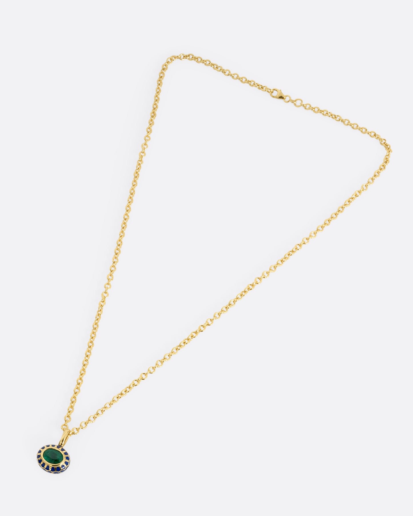 A yellow gold cable chain necklace with a pendant with a blue enamel pattern around an emerald. The pendant has a domed silhouette and floral enamel motif on its reverse. Shown from the front.