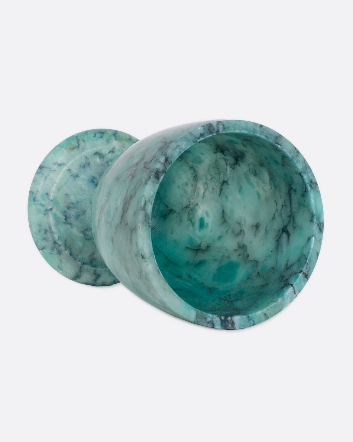 A turquoise colored ornate alabaster vessel, shown on its side from the top.