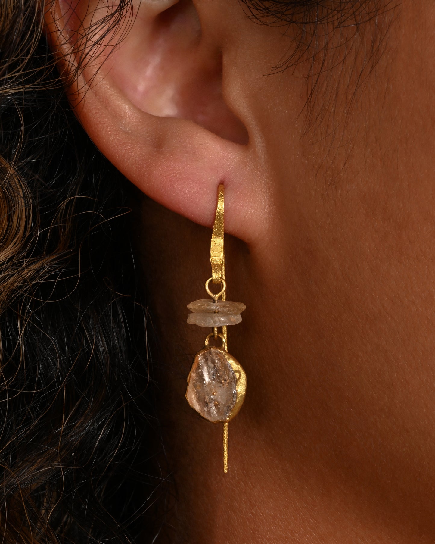 A single earring with a white quartz stack, yellow gold ear hook, and a front- facing gold wrapped quartz slice. Shown from the front on a person.