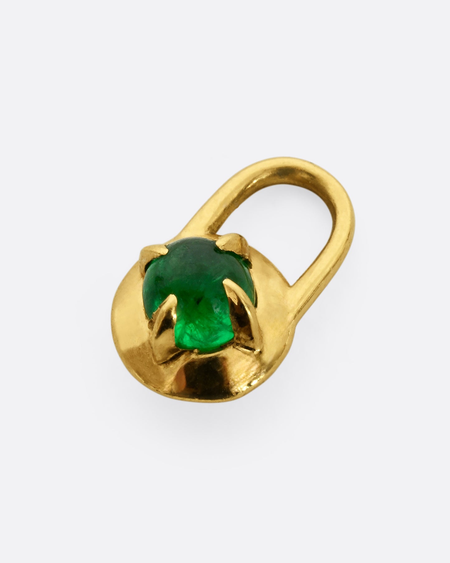 A yellow gold pendant in the shape of a lock with an emerald cabochon at the center. Shown laying flat.