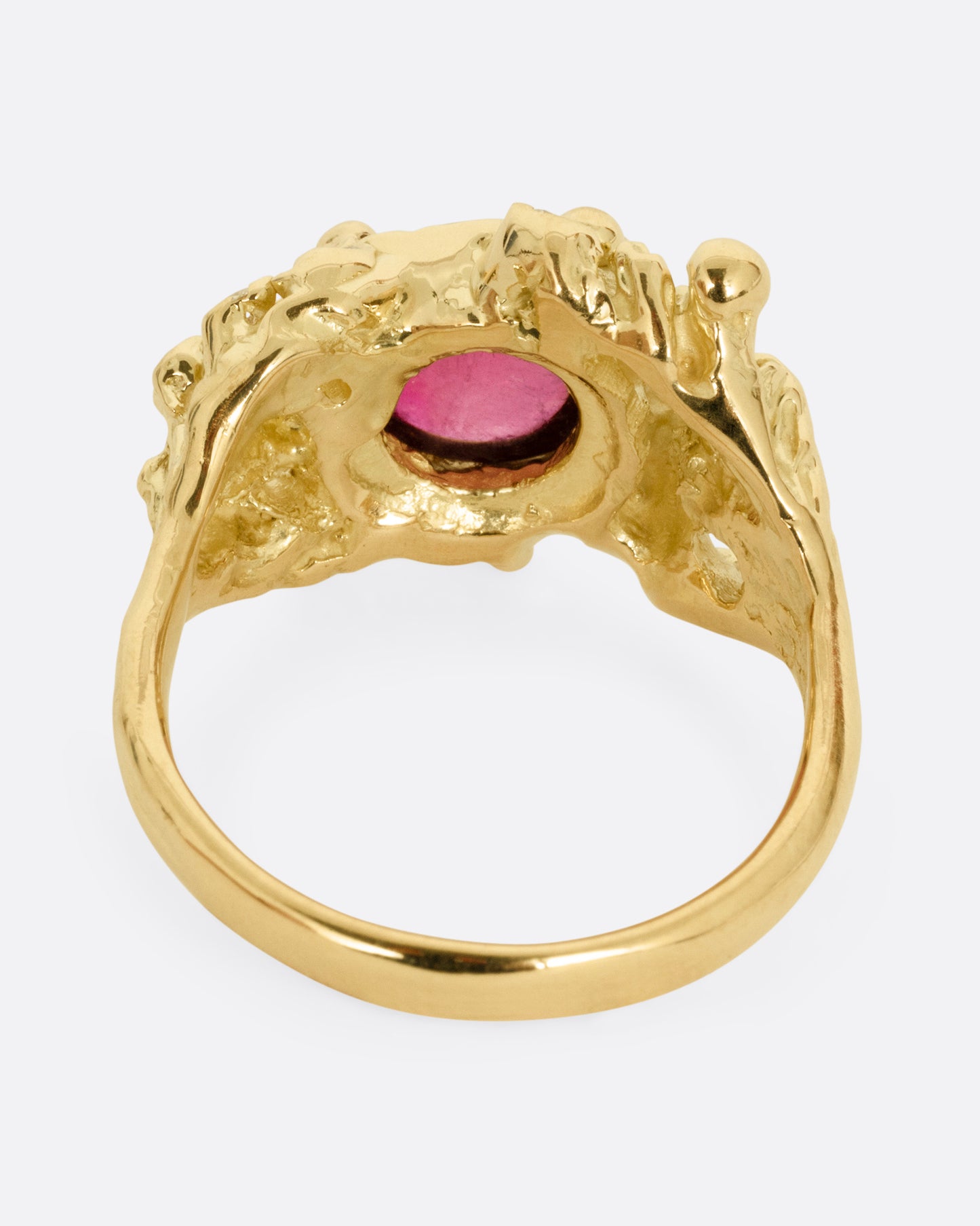A yellow gold ring with a bed of diamond tipped anemones, and a red rubellite, shown from the back.