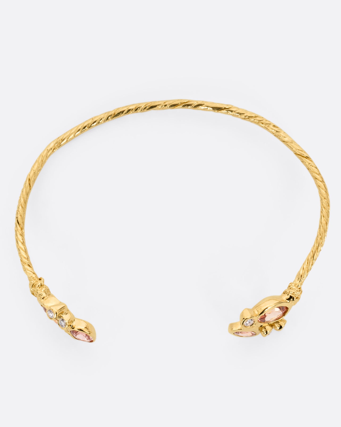 A yellow gold hand carved cuff bracelet with clusters of tourmalines and diamonds on either side of its open front, shown from the top.