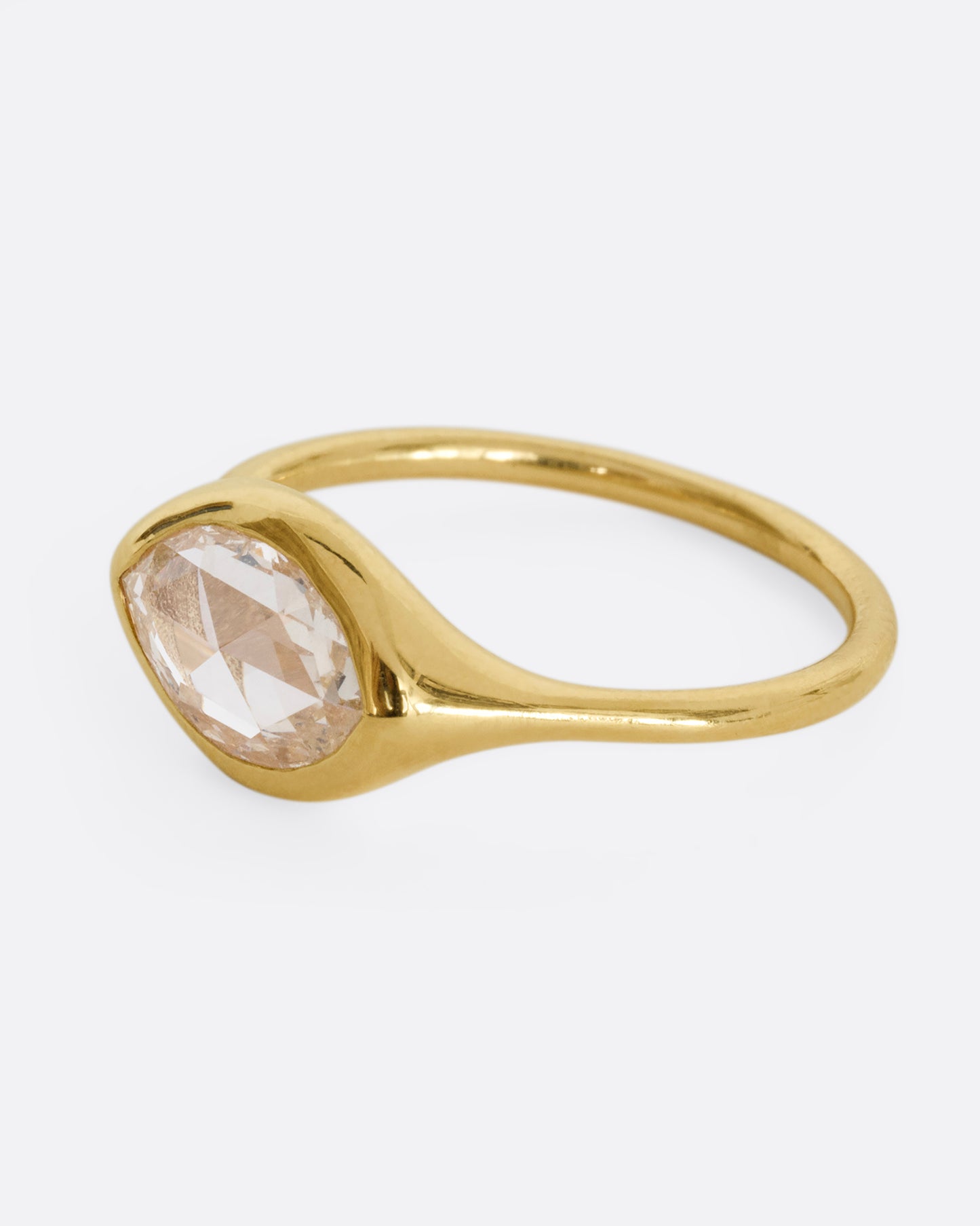 A yellow gold ring with a horizontal rose cut marquise diamond. Shown from the side.