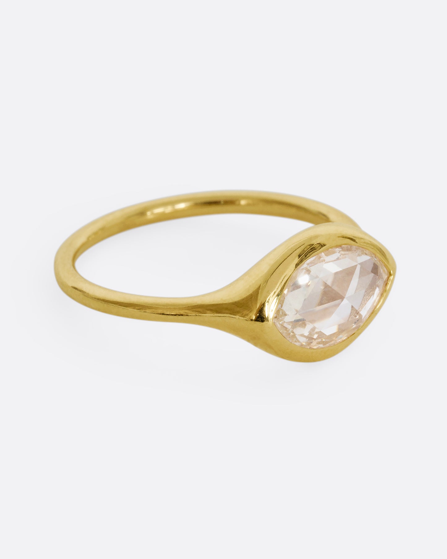 A yellow gold ring with a horizontal rose cut marquise diamond. Shown from the side.