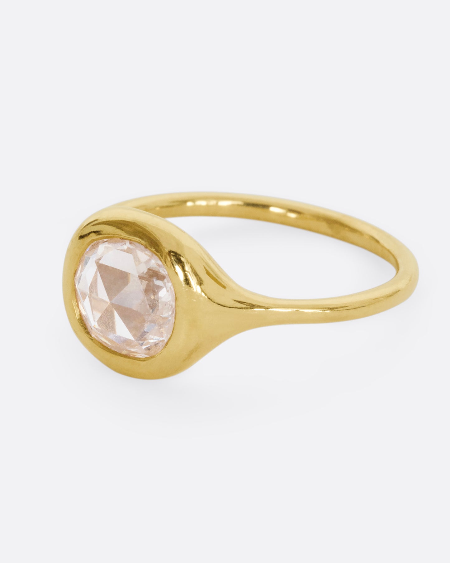 A yellow gold hand carved ring with a brilliant rose cut diamond. Shown from the side.