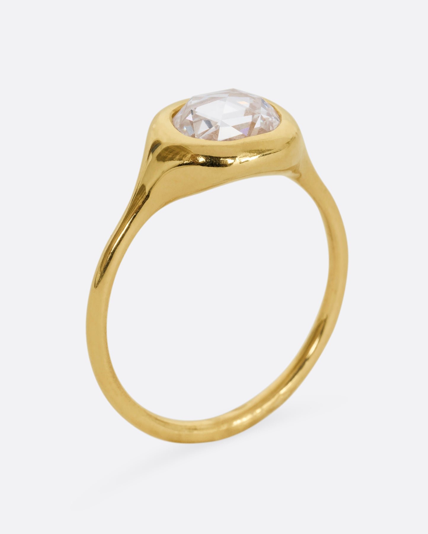 A yellow gold hand carved ring with a brilliant rose cut diamond. Shown standing up from the side.