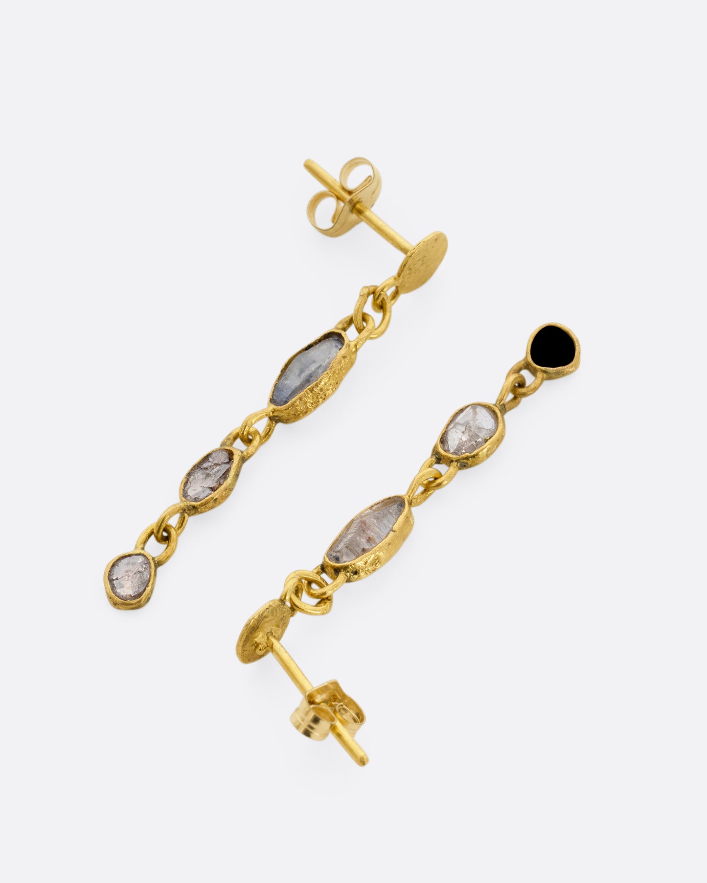 Yellow gold wrapped sapphire and diamond earrings falling from hammered gold discs. Shown from the side facing opposite directions.