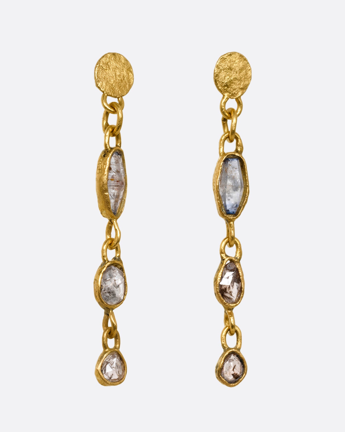 Yellow gold wrapped sapphire and diamond earrings falling from hammered gold discs. Shown from the side.