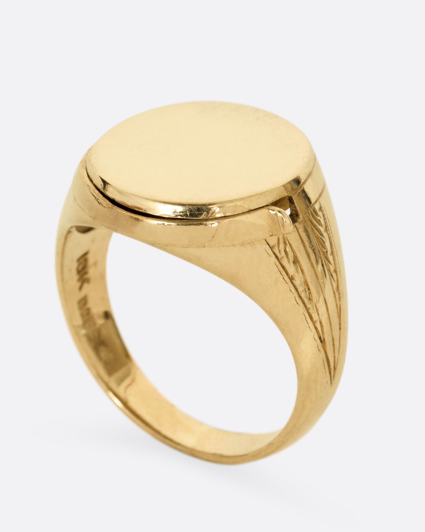 A yellow gold round-faced locket signet ring, shown closed and standing up from the side.