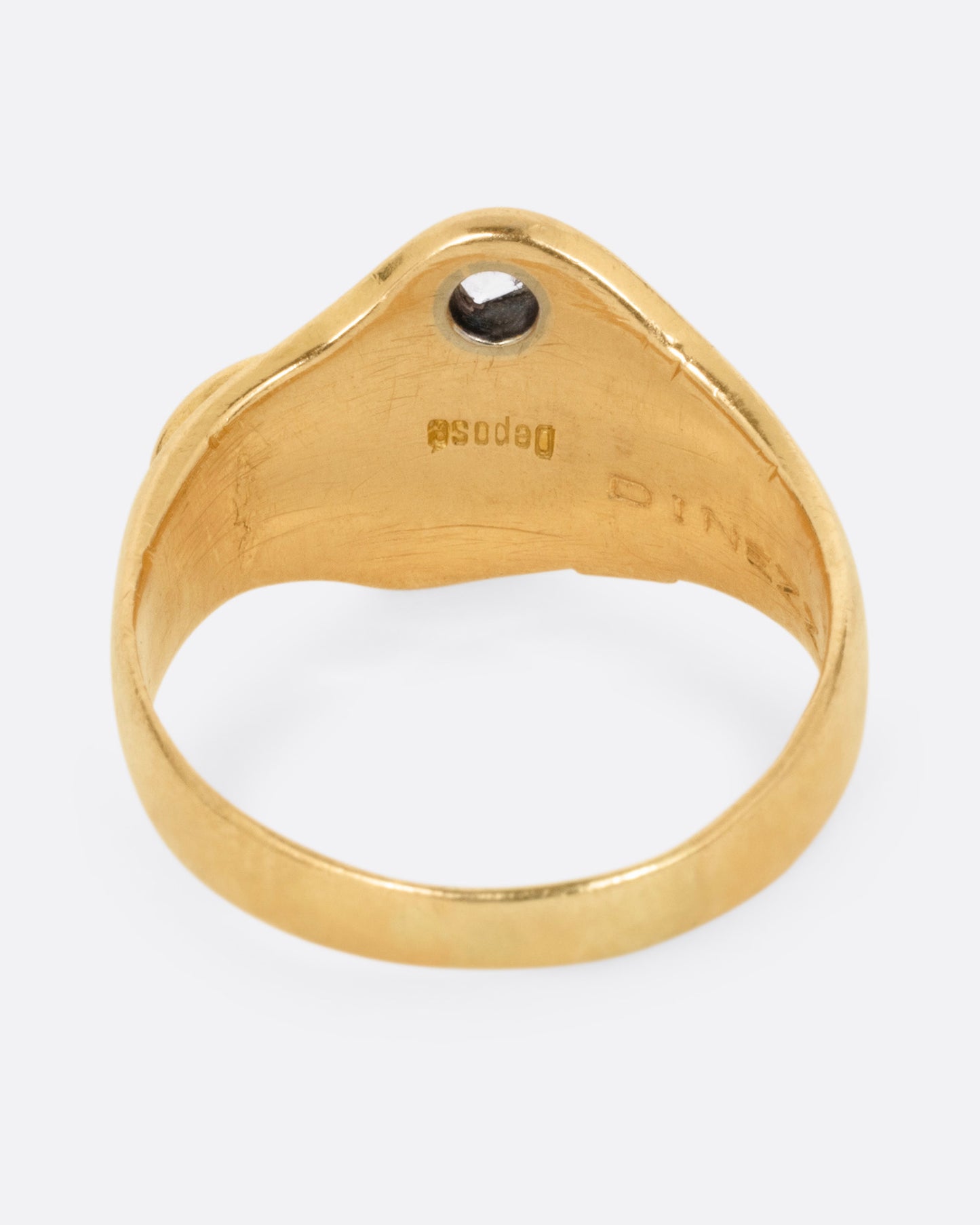 A yellow gold ring with the profile of a dog and a single diamond. Shown from the back.