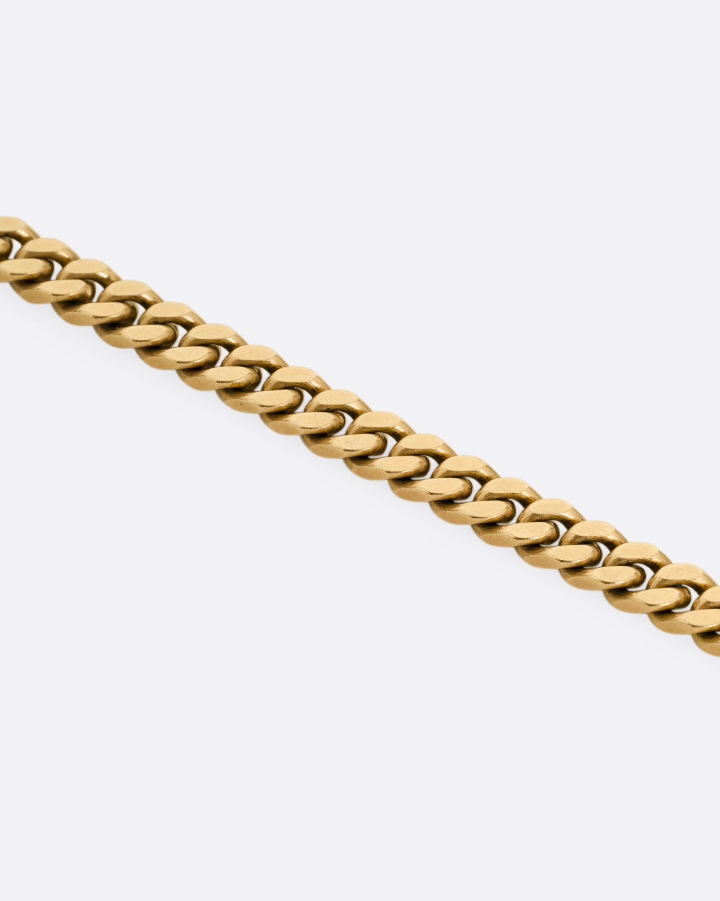 A close up of a yellow gold curb chain necklace.