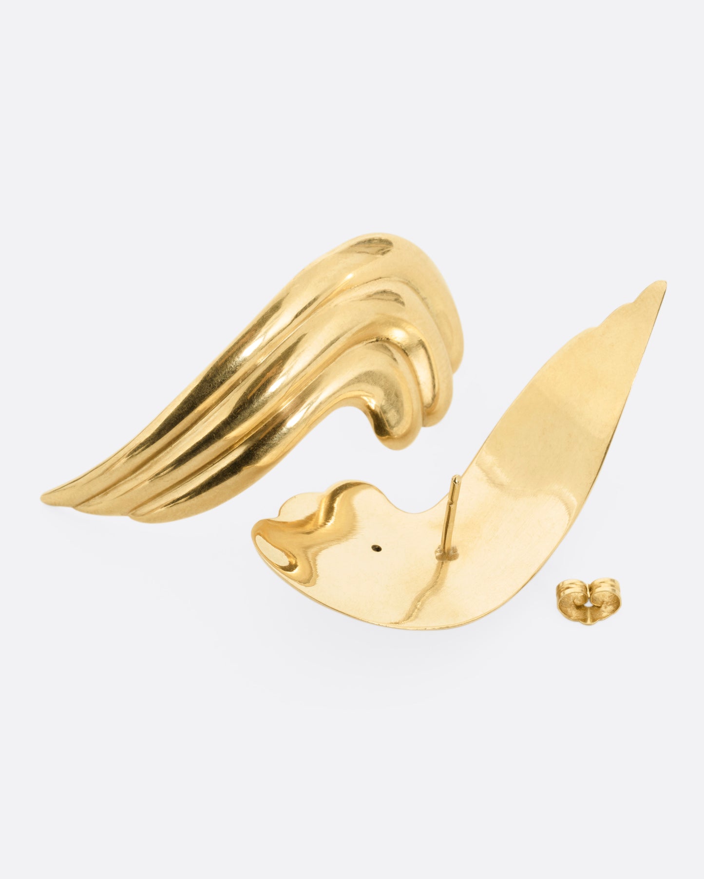 A pair of wavy yellow gold stud earrings. One earring is shown from the front, lying on its side. The other is shown from the back open.